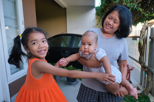 Young girl playing with her lovely little baby brother in his grandma's arms