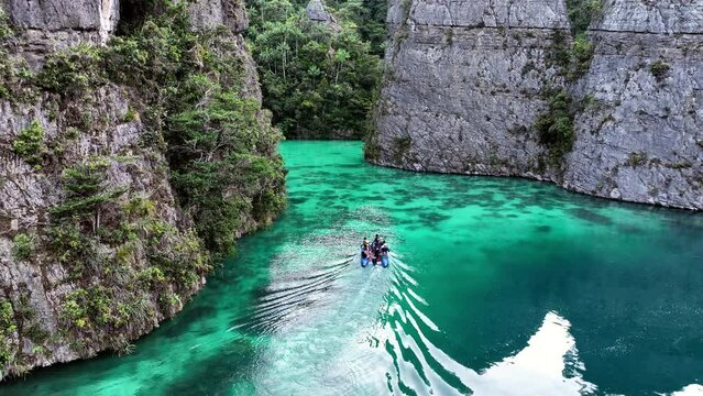 Aerial: Drone Flying Over People In Boat On Turquoise Sea Amidst Rock Formations - Raja Ampat, Indonesia