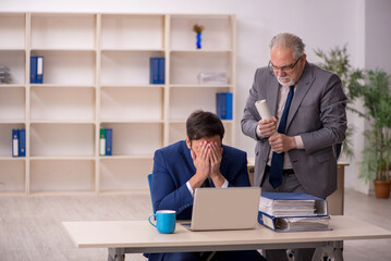 Old male boss and young male employee in the office