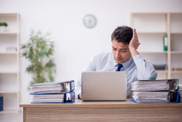 Young male employee and too much work in the office