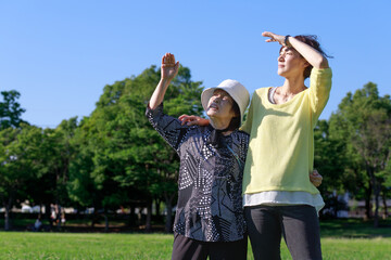 Obraz premium 紫外線と太陽光がまぶしいシニアの女性と支える娘