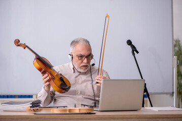 Old male music teacher in the classroom