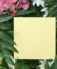 Creative layout made of flowers and leaves with paper card note. Flat lay. Nature concept