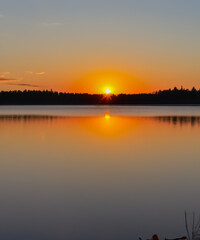 Obraz premium sunset at coast of the lake. Nature landscape. reflection, blue sky and yellow sunlight. landscape during sunset.