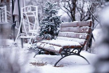 park bench on a winter alley at snowfall. bench with snow after snowstorm or in snow calamity in europe - Powered by Adobe