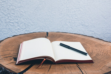 Open notebook and pen on wooden table. Notebook with blank sheets. Workplace.
