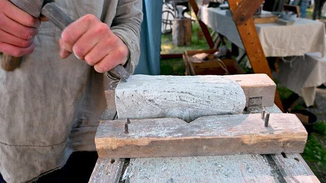 Traditional stone carving with chisel and hammer.