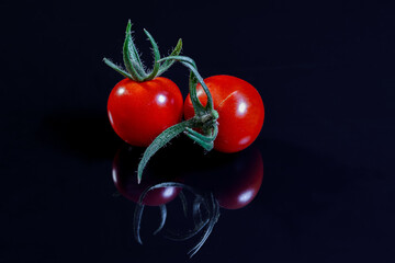 Two red tomatoes isolated on black and reflecting background. Tomatoes with clipping path.