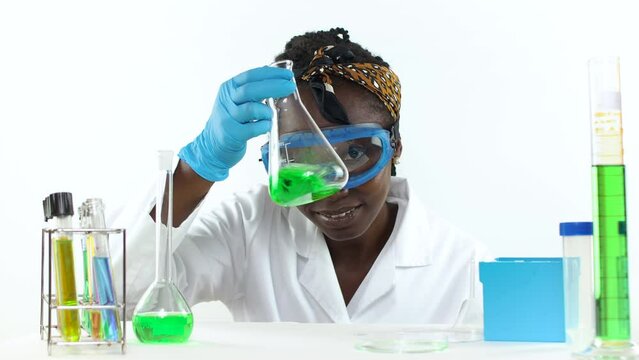 Young female scientist keenly observing a sample in an erlenmeyer flask inside a laboratory Looking at camera