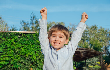 Smiling toddler boy on a green background. Two risen hands