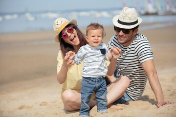 family with baby playing on the beach