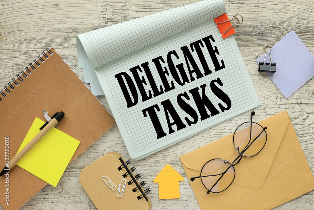 Poster notepad with a spring on the work table. words delegate tasks