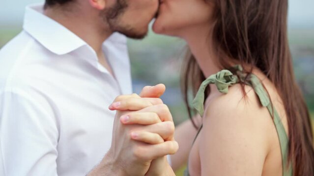 Smiling man and woman kiss with baptized hands on blurred background. Concept of romance in relationship and couple in love slow motion