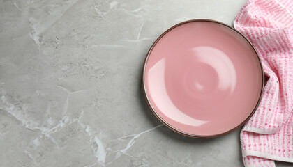 Empty plate and pink towel on light grey marble table, top view. Space for text