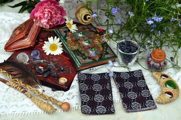 Still life with tarot cards, magic wand and book of spell on witch table in the garden. Occult,...