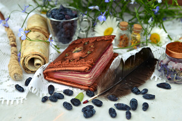 Still life with magic book of spell, manuscript and berries on the table in the garden. Occult, esoteric and witchcraft concept. Mystic wicca background with vintage objects