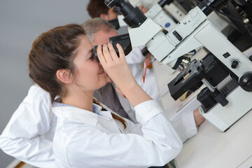 young lady looking through microscope in science lab