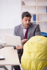 Young male employee looking after newborn at workplace