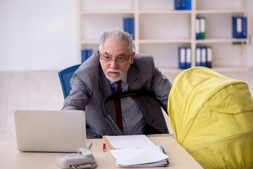 Old male employee looking after new born at workplace