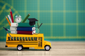 Back to school concept. Yellow school bus with books and variety school supplies over green blackboard.