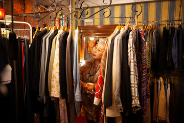 ハンガーラックから服を選ぶシニア女性