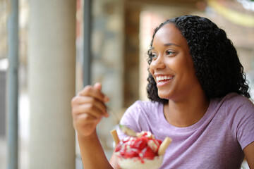 Happy black woman eating dessert looking away