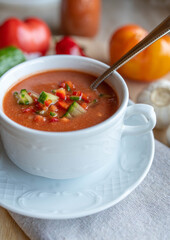 Gazpacho andalusia in a white soup cup with spoon. Delicious and healthy cold vegetable soup with raw vegetables. 