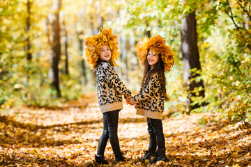 Two happy children walk in the autumn park, holding hands. Kids play in autumn park.