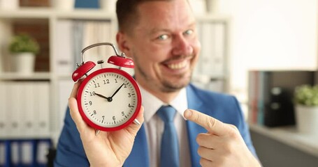 Happy professional man pointing finger at alarm clock. Business punctuality and time management