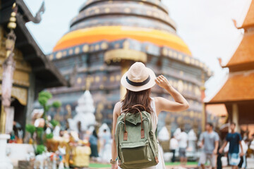 Young asian woman traveler in white dress with hat and bag traveling in Wat Phra That Lampang Luang, Tourist visit at Lampang, Thailand.. Asia Travel, Vacation and summer holiday concept - obrazy, fototapety, plakaty