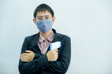 Man in black suit holding thermometer, standing in front of white background