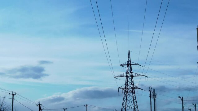 Time Lapse of White Clouds and Blue Sky over the Power Line, Electricity, High-Voltage Pole. Transforming White Clouds and Blue Sunny Sky over a High-Voltage Pole and Wires.