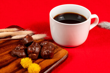 赤い絨毯に配置されたコーヒーとチョコレート、冬っぽいドライフラワーを添えて