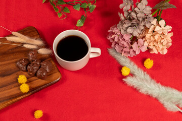 Obraz na płótnie Canvas 赤い絨毯に配置されたコーヒーとチョコレート、冬っぽいドライフラワーを添えて
