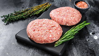 Raw chicken patty, ground meat cutlets on a chopping Board. Organic mince. Black background. Top...