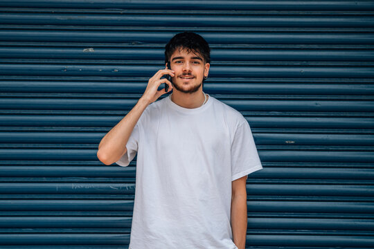 young man or teenager with mobile phone in the street