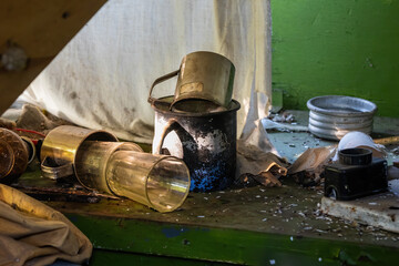 Dirty table with iron mugs and glasses in an old abandoned house