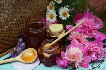 Still life with natural honey in jar, dipper, peony and stick on wooden background outside. Countryside summer rural background, vintage concept, healthy food