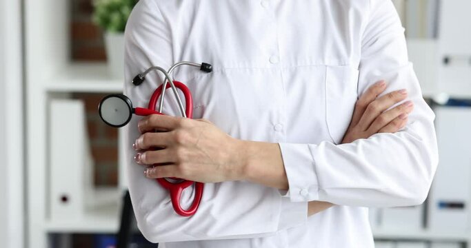 Woman doctor holding red stethoscope in her hands closeup 4k movie slow motion. Therapeutic medical care concept