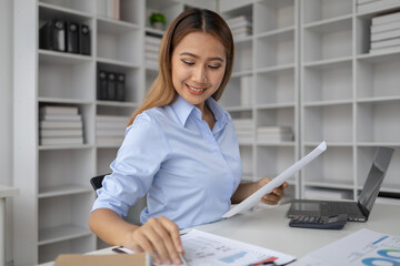 Asian woman working in startup company office, businesswoman checking documents and company performance report to analyze and find ways to grow company. Business administration concept.