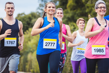 Group of runners in fitness clothing running at marathon race