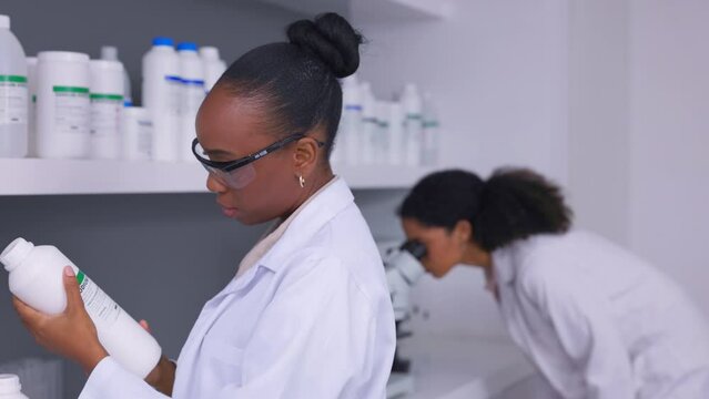 Chemicals, reading and woman scientist in a laboratory for experiment, research or study. Science, professional and young African female chemist checking liquid pharmaceutical products for inventory.