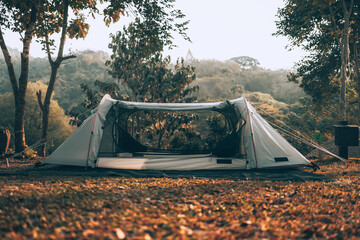 Gray tent on the grass in the forest The view behind is the mountain in the morning. Camping,...