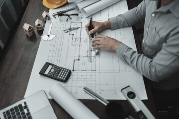Architect engineer use pen and mini T-slide drawing design working on blueprint. House planning design and construction concept.