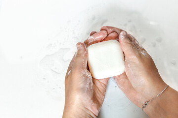 Close-up of a young woman's hands with a piece of handmade soap on a white background.Hand washing...