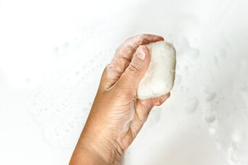 Close-up of a young woman's hands with a piece of handmade soap on a white background.Hand washing with soap. He washes his hands.