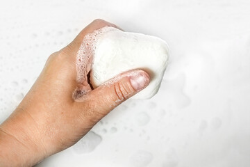 Close-up of a young woman's hands with a piece of handmade soap on a white background.Hand washing...