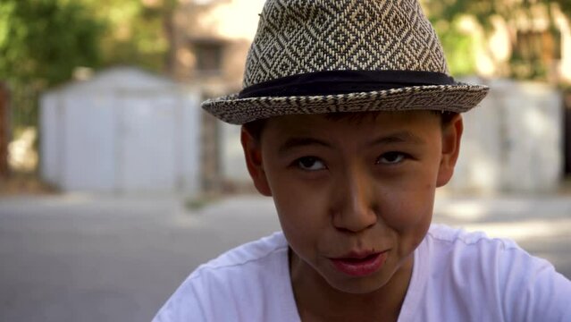 a small asian a boy with cap beatboxing in a street like a pro