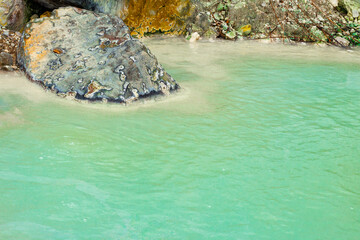 close-up of a cobalt blue hot spring with a large hot spring rock
