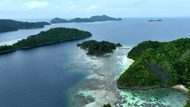 Aerial Forward Shot Of Green Archipelago On Sea Against Cloudy Sky - Raja Ampat, Indonesia